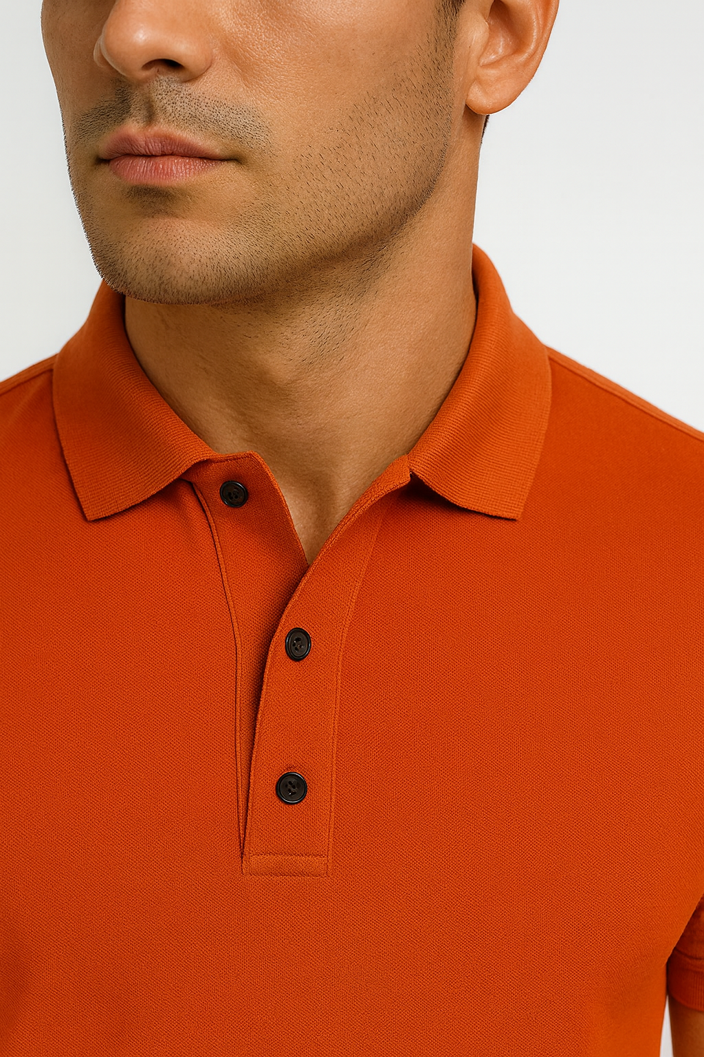 Close-up of a person wearing an orange polo shirt with black buttons on a light gray background