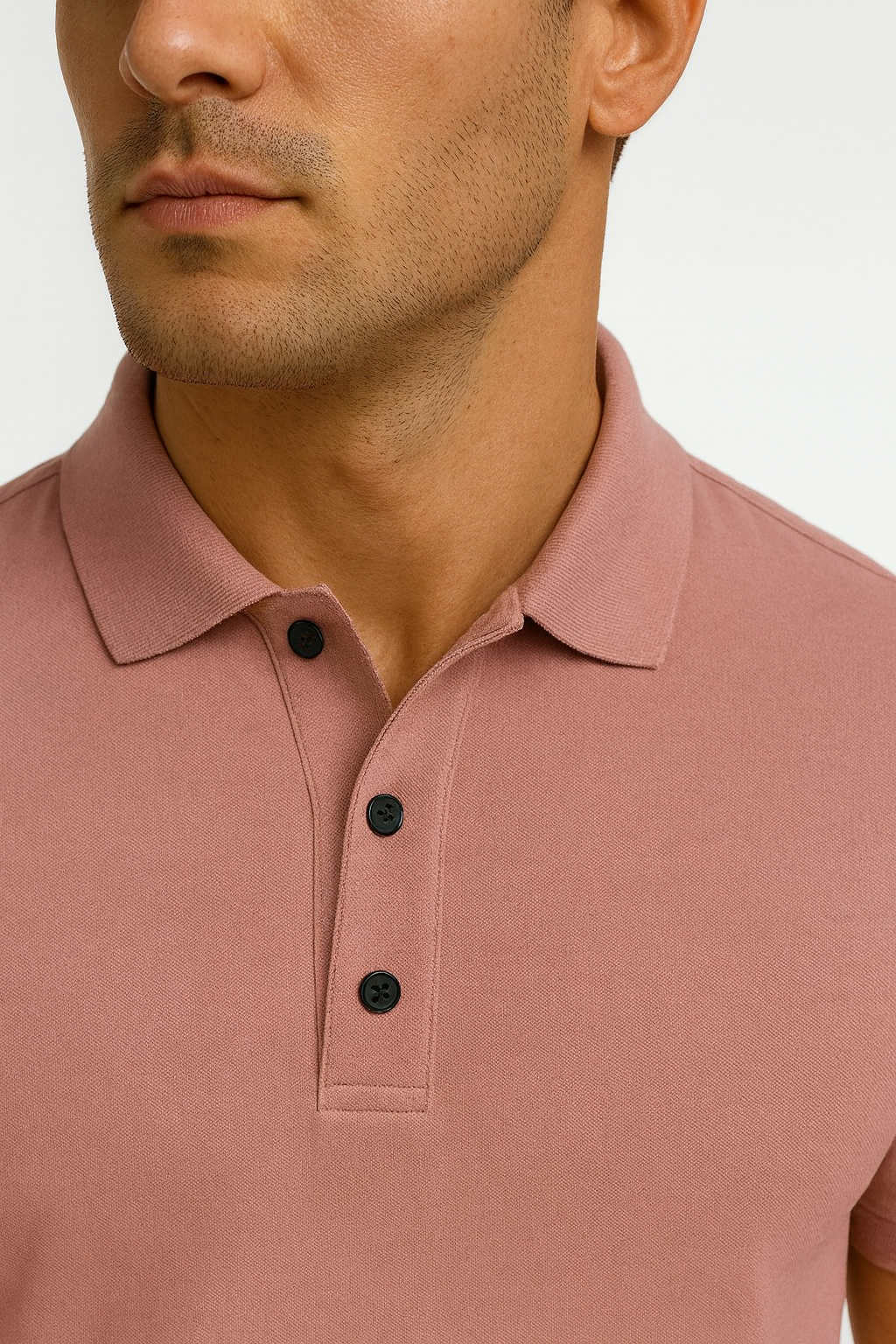 Close-up of a man wearing a pink polo shirt with black buttons on a white background