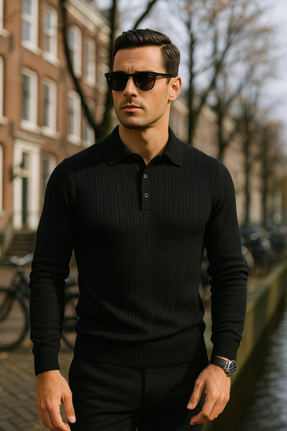 Man wearing a black sweater and sunglasses standing on a street with buildings in the background