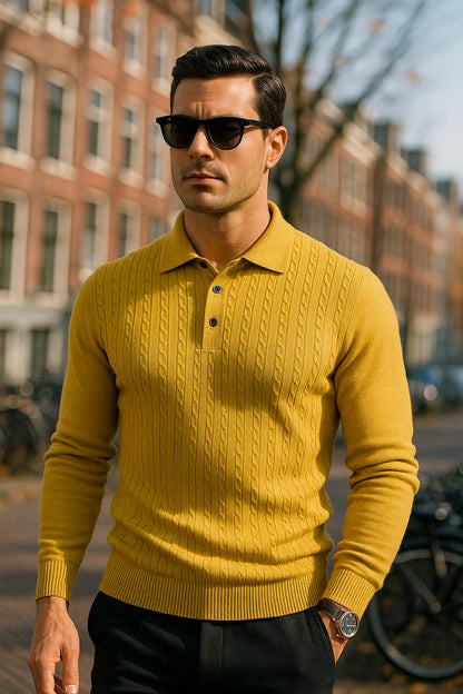 Man wearing a yellow sweater and sunglasses standing on a street with buildings in the background