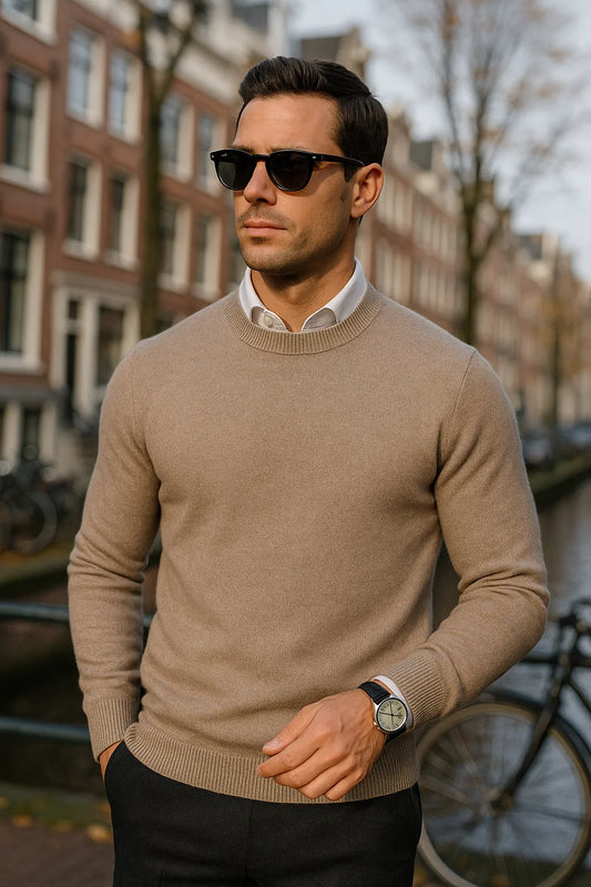 Man wearing a beige sweater and sunglasses in an urban setting