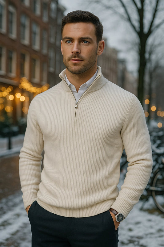 Man wearing a beige sweater in an urban setting with blurred lights and trees.