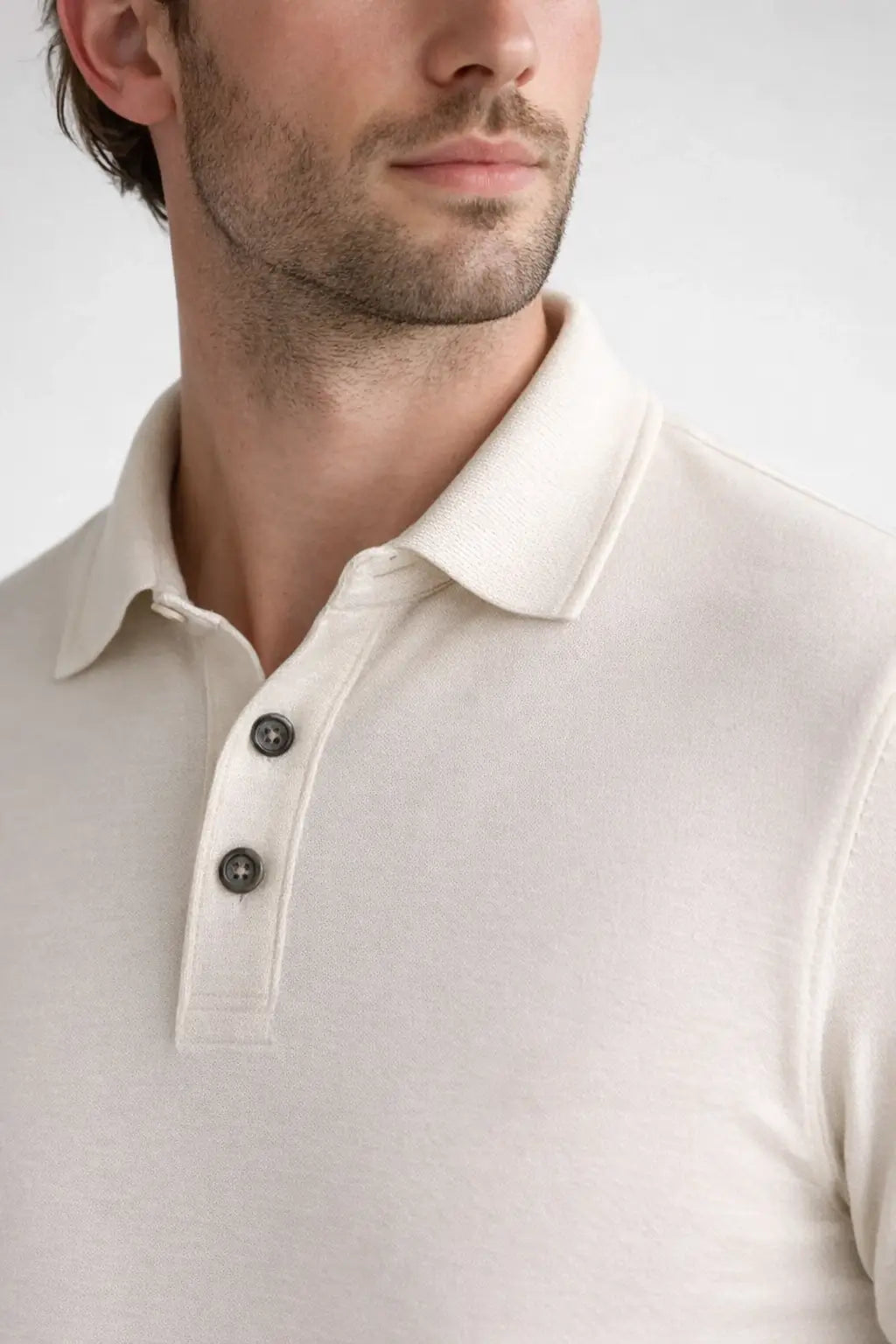 Close-up of a person wearing a beige polo shirt with a white background
