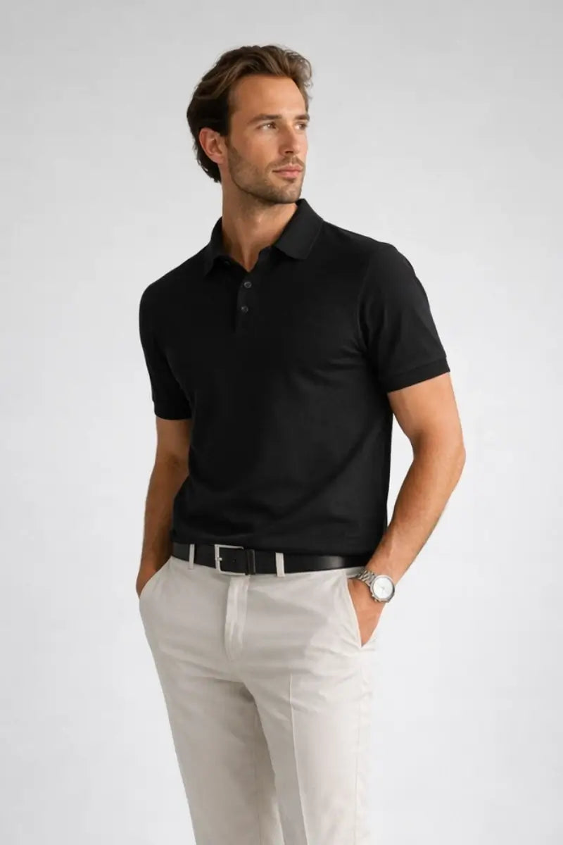 Man wearing a black polo shirt and light gray pants on a white background