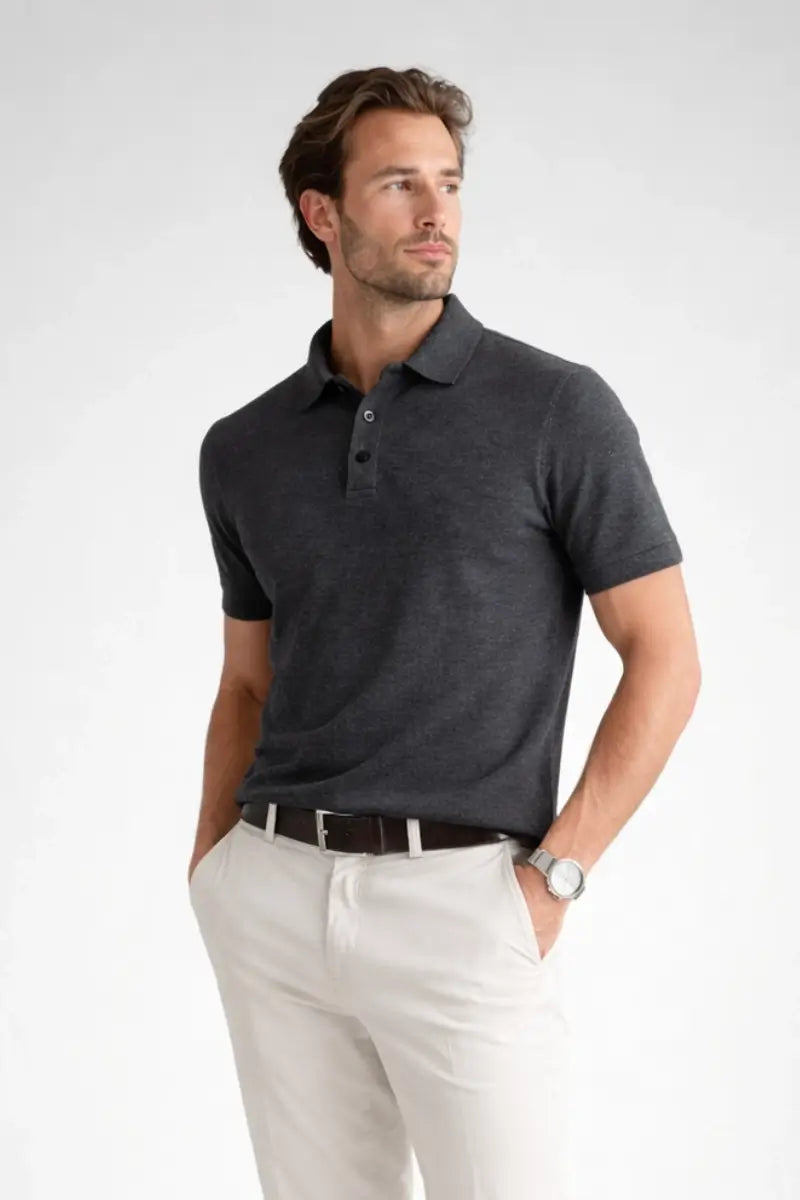 Man wearing a dark gray polo shirt and white pants on a light gray background