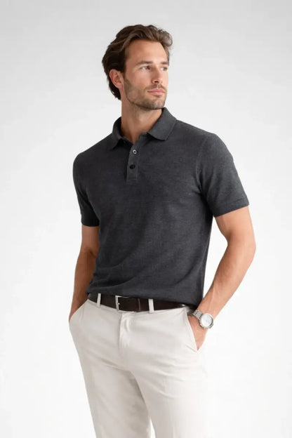 Man wearing a dark gray polo shirt and white pants on a light gray background