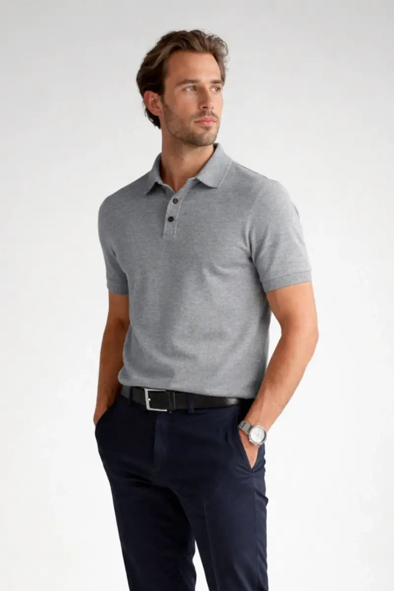 Man wearing a gray polo shirt and navy pants on a white background