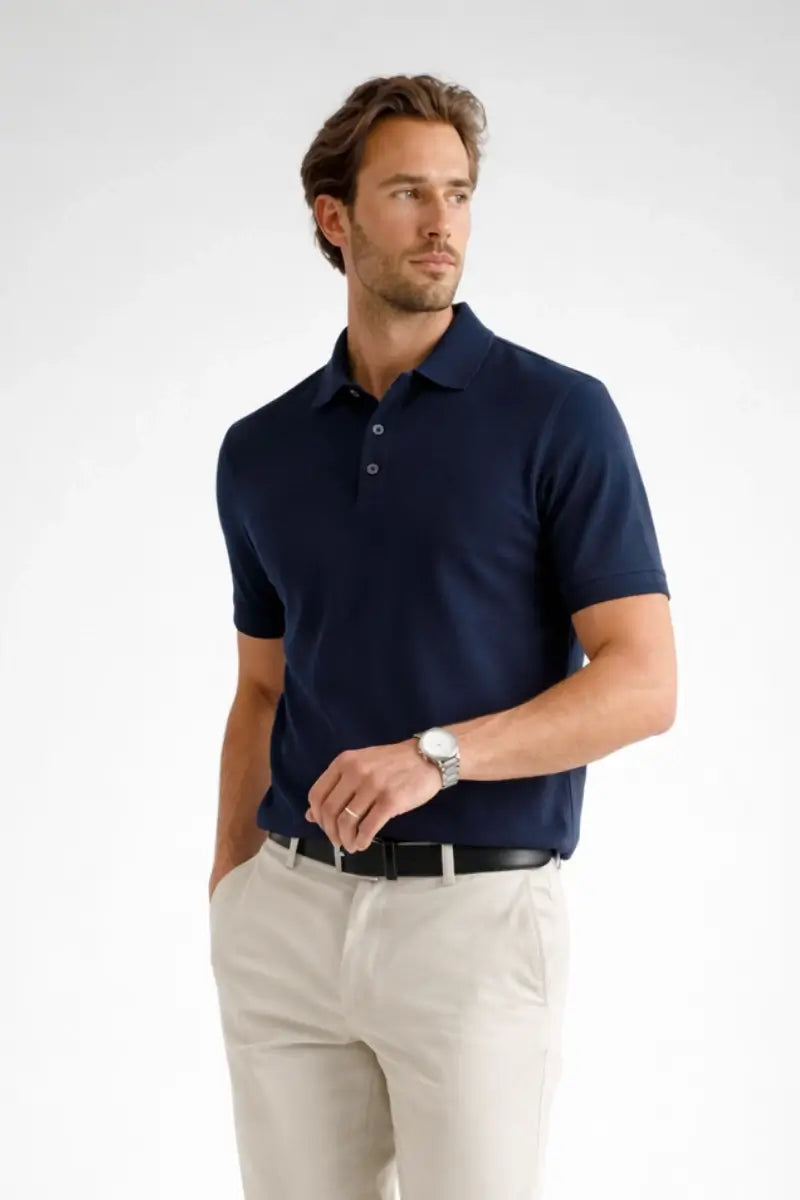 Man wearing a navy polo shirt and light-colored pants on a white background