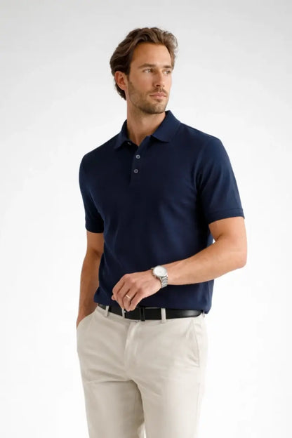 Man wearing a navy polo shirt and light-colored pants on a white background