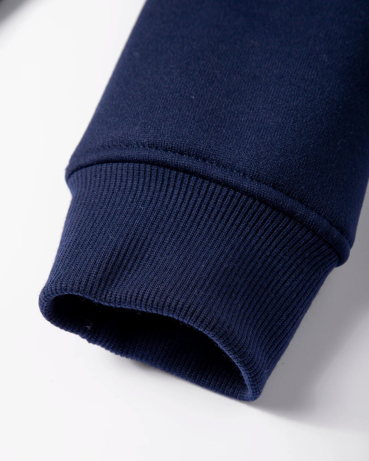 Close-up of a navy blue sweater sleeve on a white background