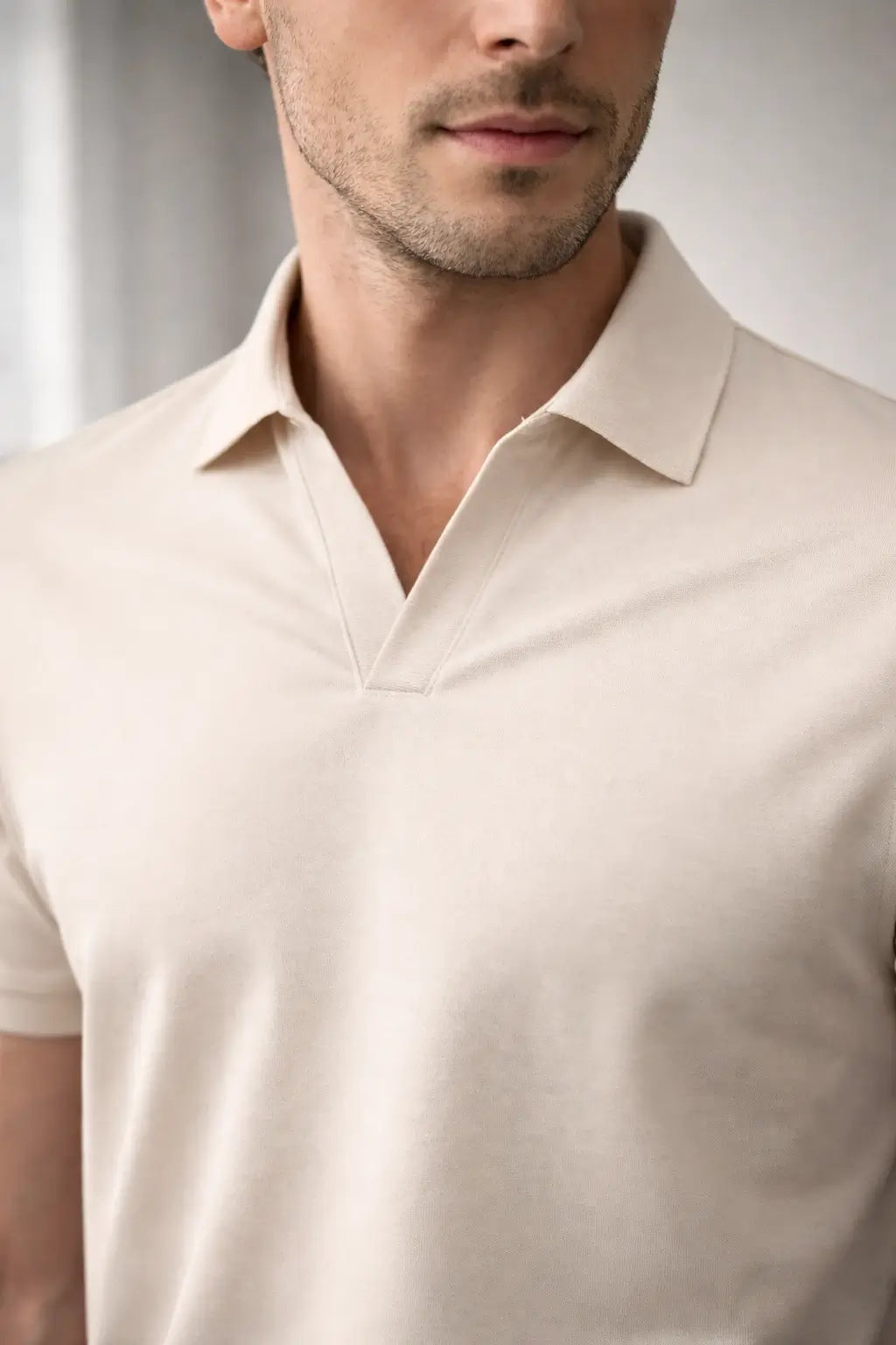 Man wearing a beige polo shirt against a neutral background