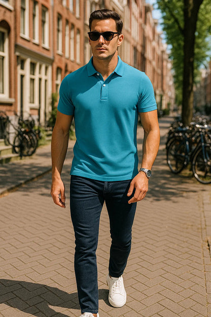 Man wearing a blue polo shirt and dark jeans walking on a sidewalk with bicycles and buildings in the background.