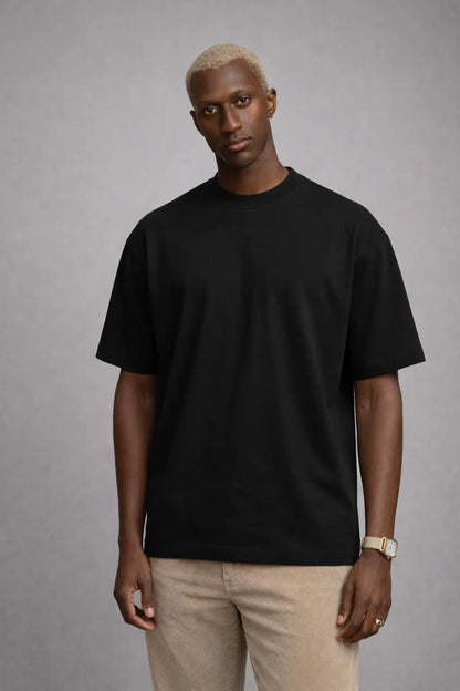 Man wearing a black t-shirt and beige pants against a gray background