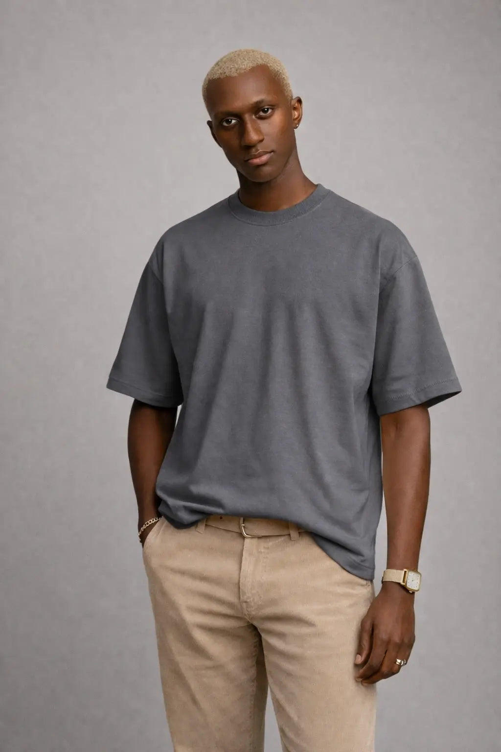 Man wearing a gray t-shirt and beige pants against a gray background