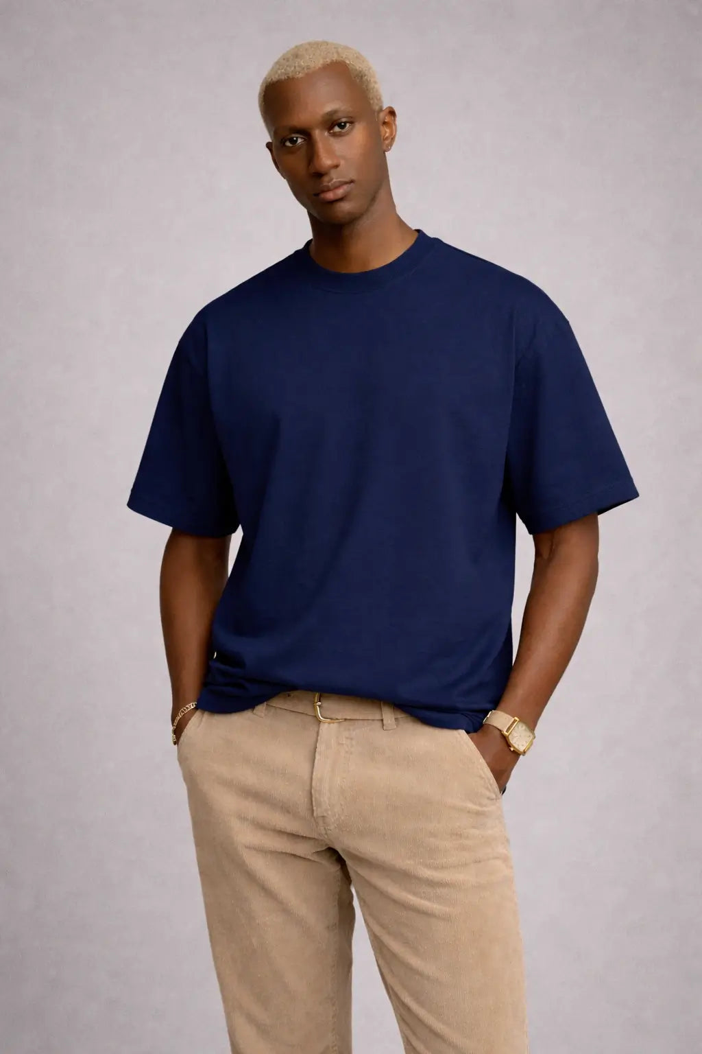 Man wearing a navy blue t-shirt and beige pants against a gray background