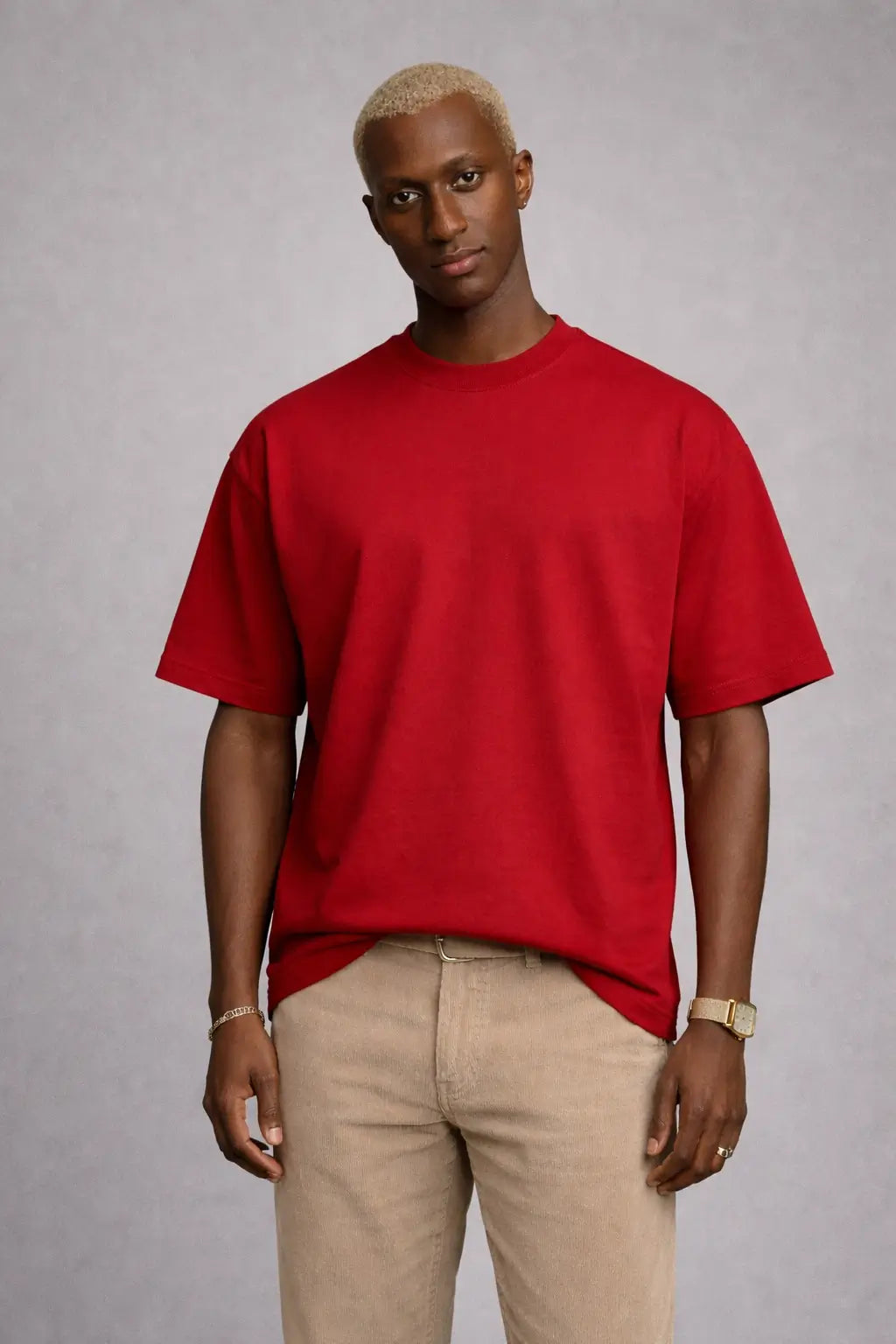 Man wearing a red t-shirt and beige pants against a gray background