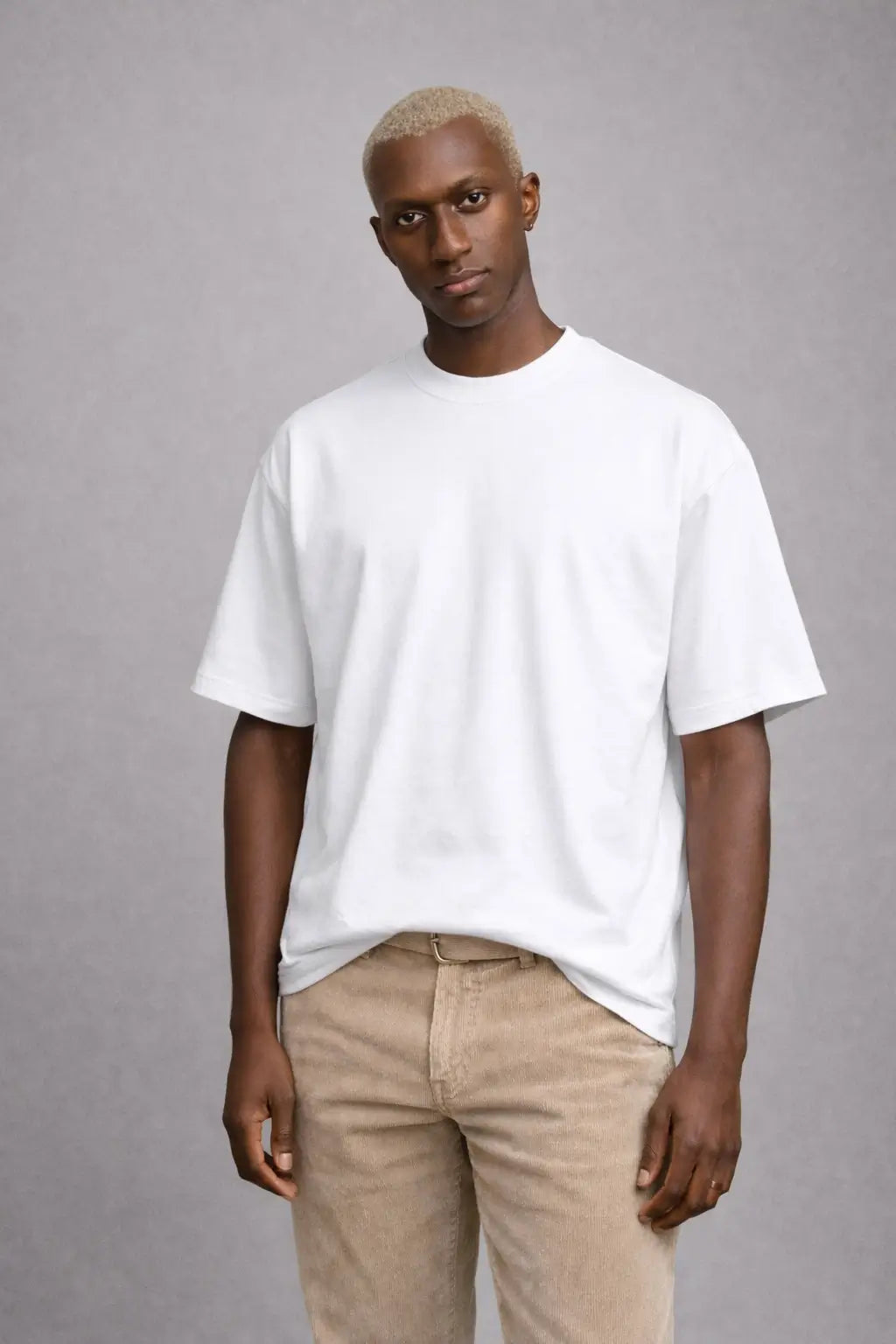 Man wearing a white t-shirt and beige pants against a gray background
