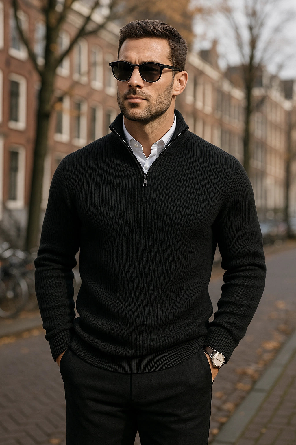 Man wearing a black sweater and sunglasses standing on a street with buildings in the background