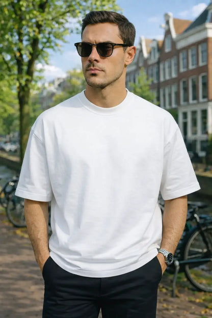 Man wearing a white t-shirt and sunglasses with a cityscape background